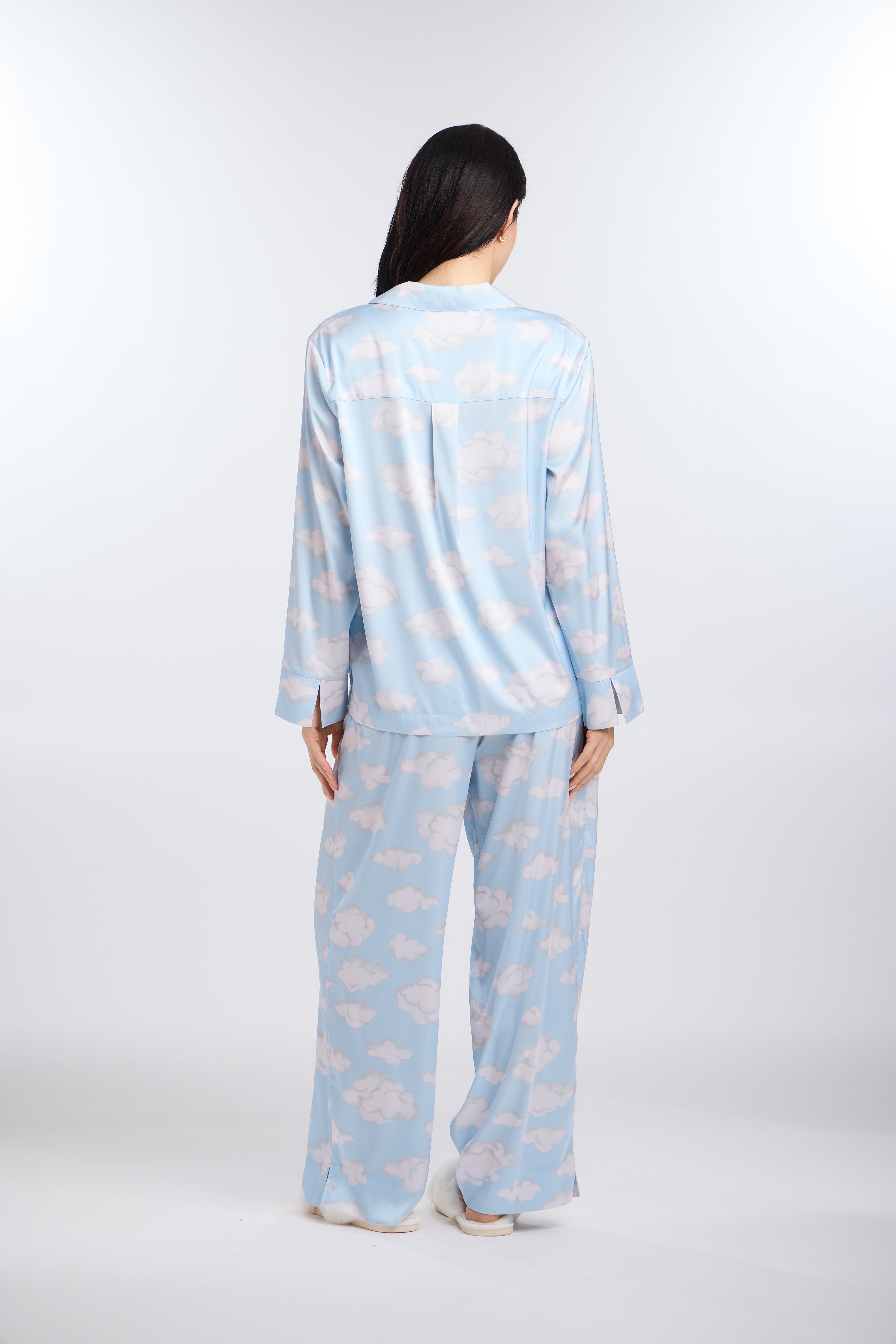 Person wearing a light blue pajama set with cloud pattern on a white background