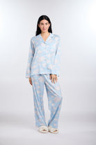 Woman wearing a light blue pajama set with cloud pattern on a white background