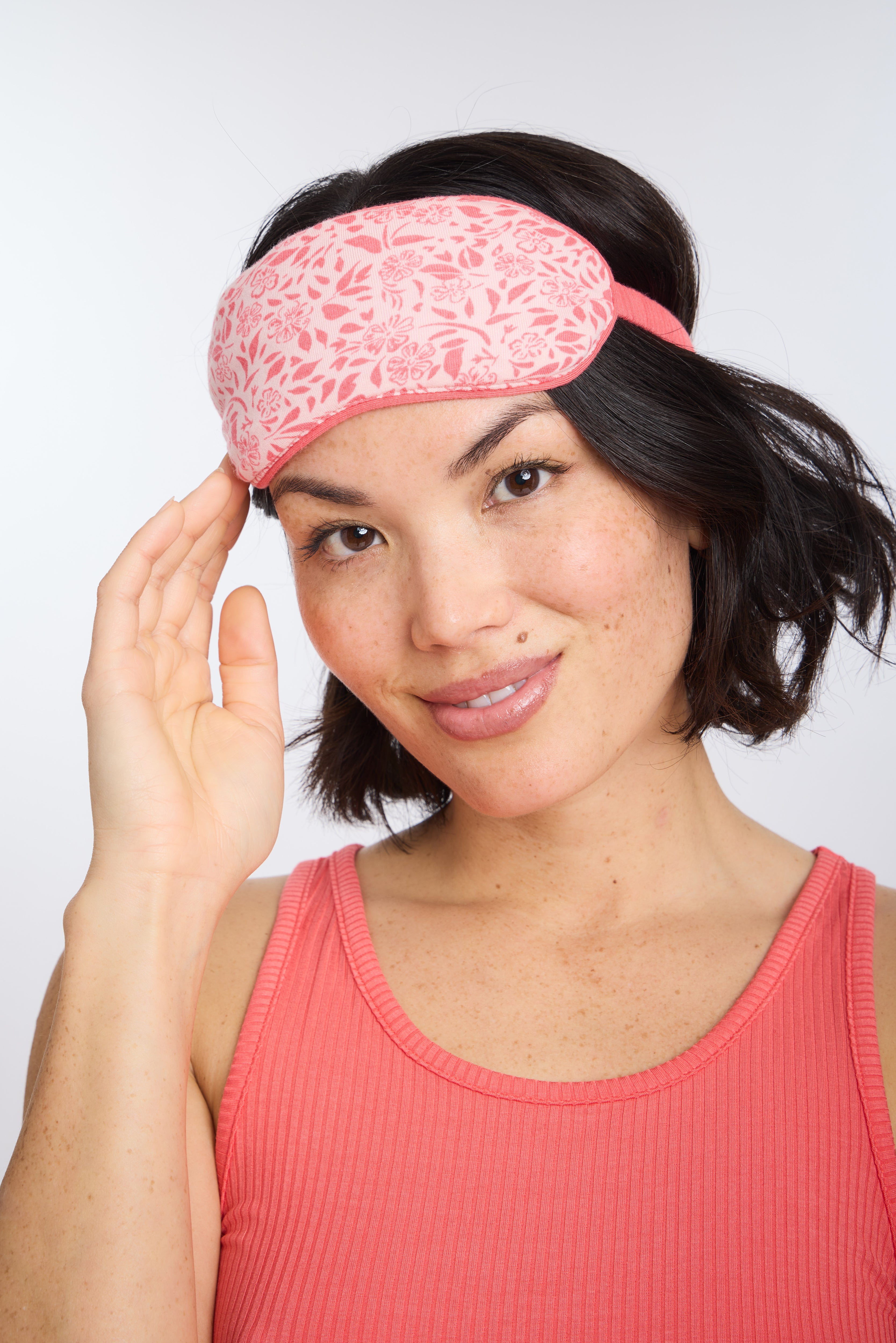 Model wearing Ditsy Blossoms Eye mask with Hot Coral Racerback Tank
